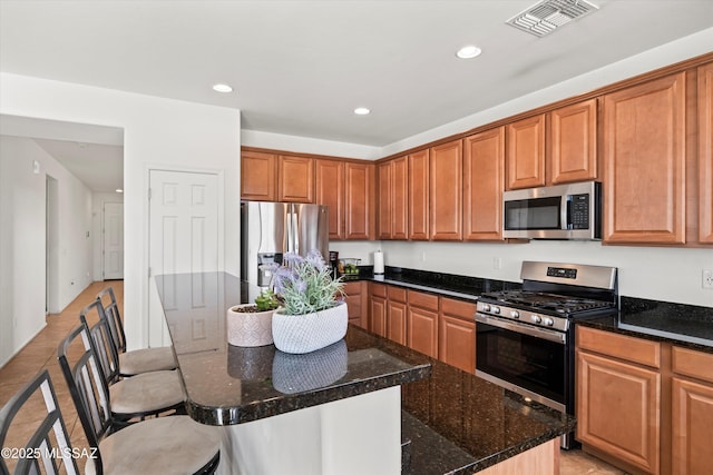 kitchen with visible vents, a kitchen island, a breakfast bar, recessed lighting, and stainless steel appliances