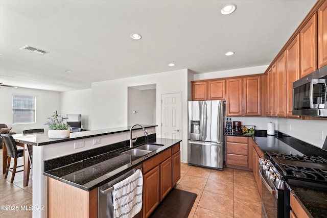 kitchen featuring open floor plan, dark stone counters, recessed lighting, stainless steel appliances, and a sink