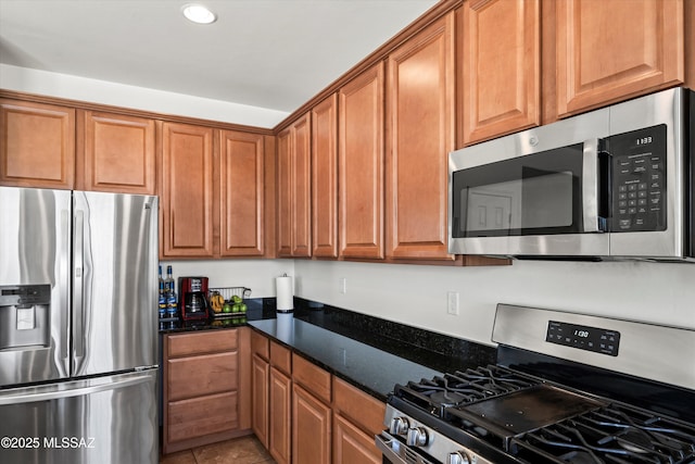 kitchen with dark stone countertops, light tile patterned flooring, recessed lighting, appliances with stainless steel finishes, and brown cabinets