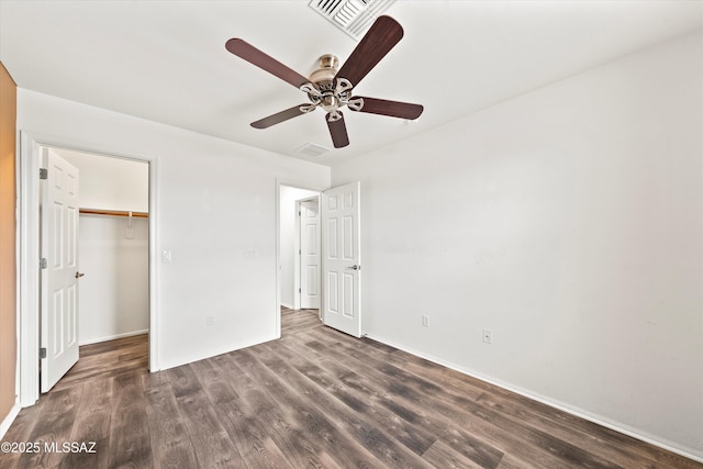 unfurnished bedroom featuring visible vents, dark wood-type flooring, a ceiling fan, a closet, and a spacious closet