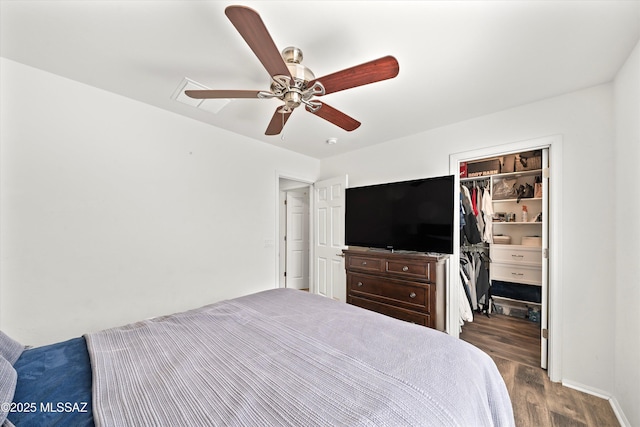 unfurnished bedroom featuring a closet, a ceiling fan, dark wood-style floors, and a spacious closet