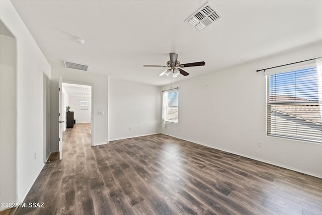unfurnished room with ceiling fan, visible vents, baseboards, and dark wood-style floors