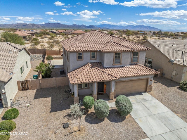 mediterranean / spanish house with fence, driveway, stucco siding, a tiled roof, and a mountain view