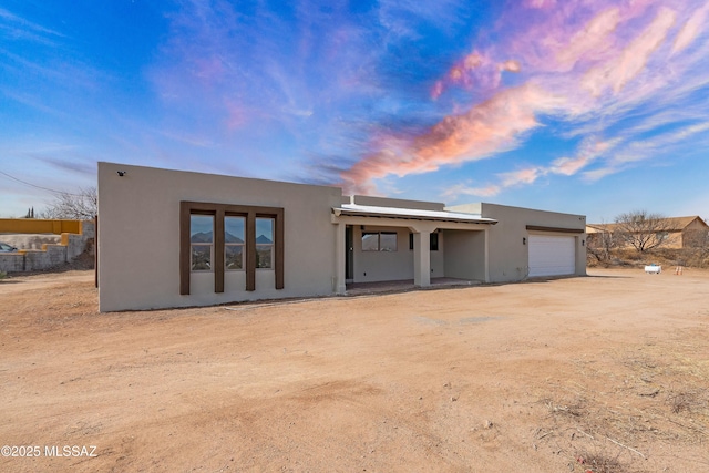 rear view of property featuring a garage and stucco siding