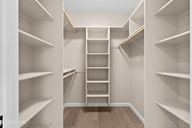 walk in closet with wood finished floors