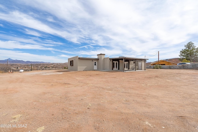 rear view of house with a patio, a mountain view, and stucco siding