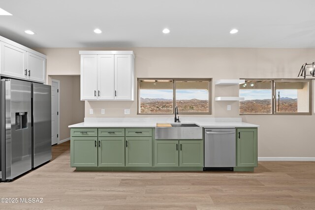 kitchen featuring appliances with stainless steel finishes, white cabinetry, green cabinets, and a sink