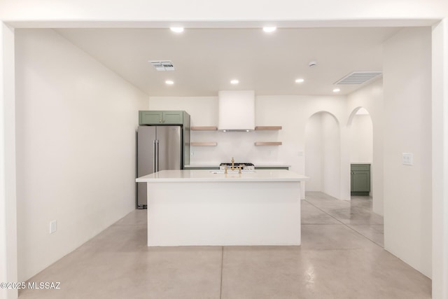 kitchen featuring visible vents, freestanding refrigerator, light countertops, concrete flooring, and exhaust hood