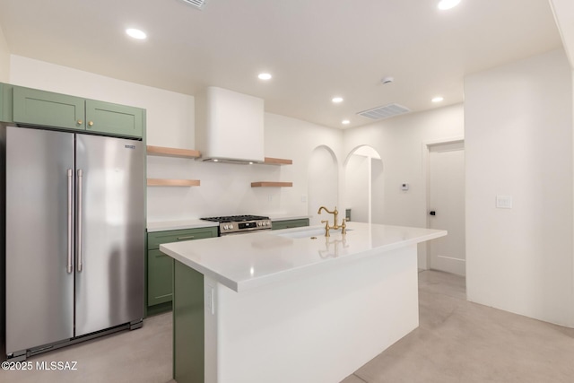 kitchen with green cabinetry, stainless steel appliances, open shelves, and wall chimney exhaust hood