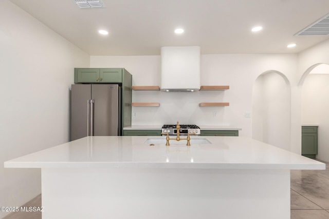 kitchen with open shelves, a sink, stainless steel appliances, green cabinets, and exhaust hood