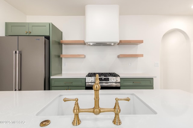 kitchen with stainless steel appliances, green cabinets, extractor fan, and light countertops