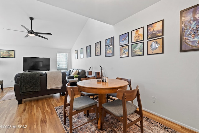 dining space featuring baseboards, lofted ceiling, a ceiling fan, and light wood finished floors