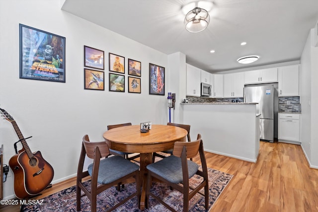 dining space featuring light wood-style flooring and baseboards