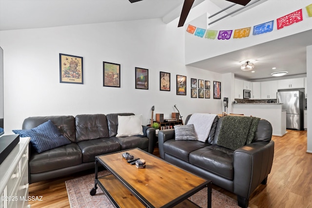 living room featuring light wood-style flooring and vaulted ceiling with beams