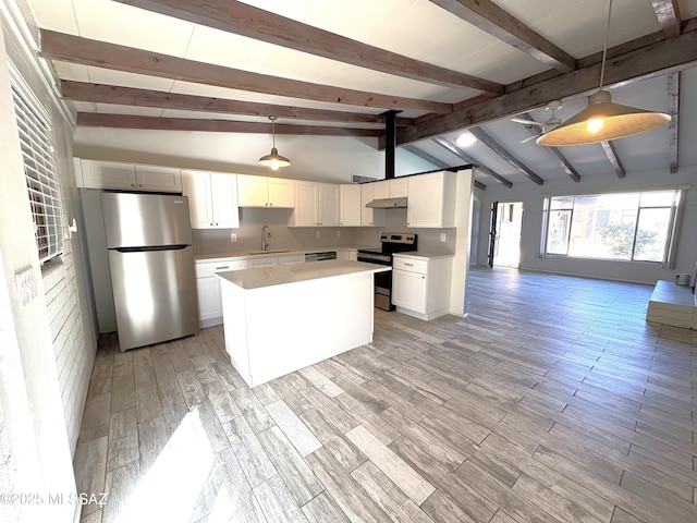 kitchen featuring vaulted ceiling with beams, a sink, stainless steel appliances, light countertops, and open floor plan