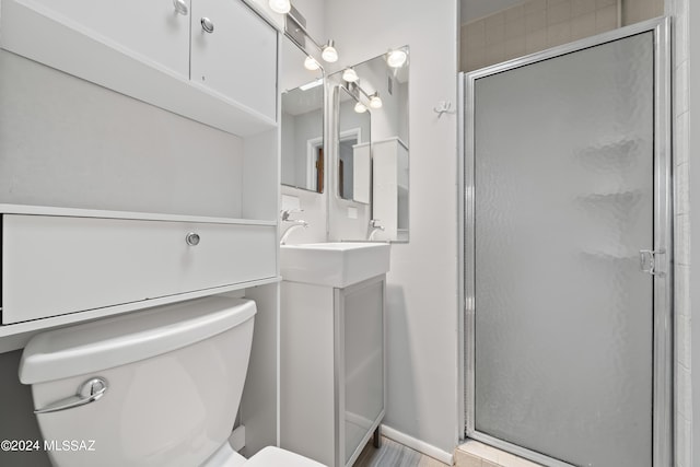 full bathroom with a stall shower, toilet, baseboards, and a sink