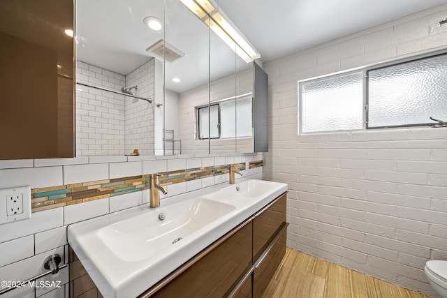 bathroom featuring visible vents, a sink, wood finished floors, double vanity, and walk in shower