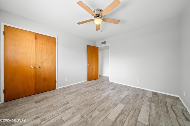 unfurnished bedroom featuring baseboards, visible vents, ceiling fan, a closet, and light wood-type flooring