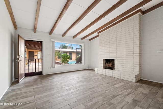 unfurnished living room featuring wood finished floors, a fireplace, and vaulted ceiling with beams