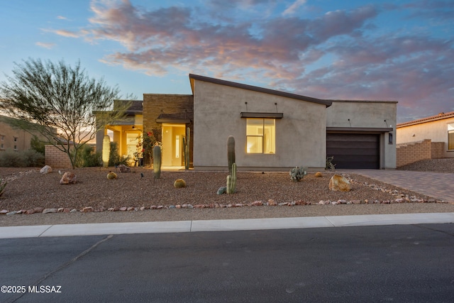 contemporary house featuring stucco siding, an attached garage, and driveway