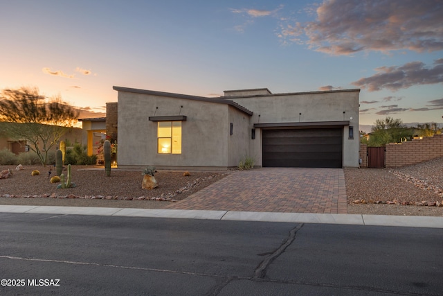 modern home featuring decorative driveway, a garage, and stucco siding