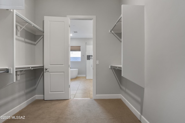 walk in closet featuring light colored carpet