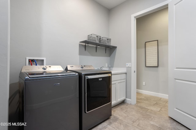 laundry area featuring baseboards, cabinet space, and separate washer and dryer