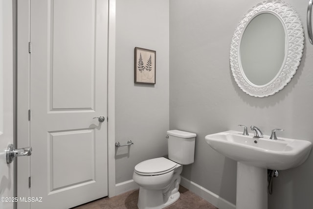 bathroom featuring tile patterned floors, toilet, baseboards, and a sink