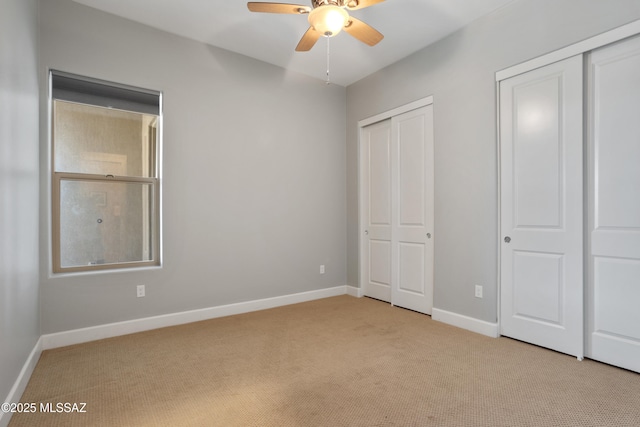 unfurnished bedroom with carpet flooring, baseboards, and two closets