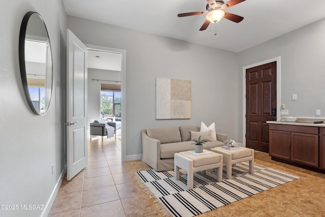 living area with light tile patterned floors, baseboards, and ceiling fan