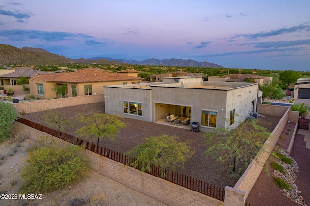 view of front of house featuring a patio area, stucco siding, a mountain view, and a fenced backyard