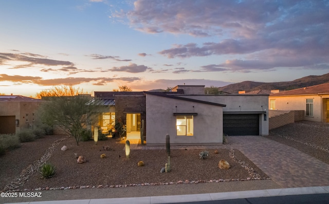 view of front of home featuring decorative driveway, an attached garage, and stucco siding