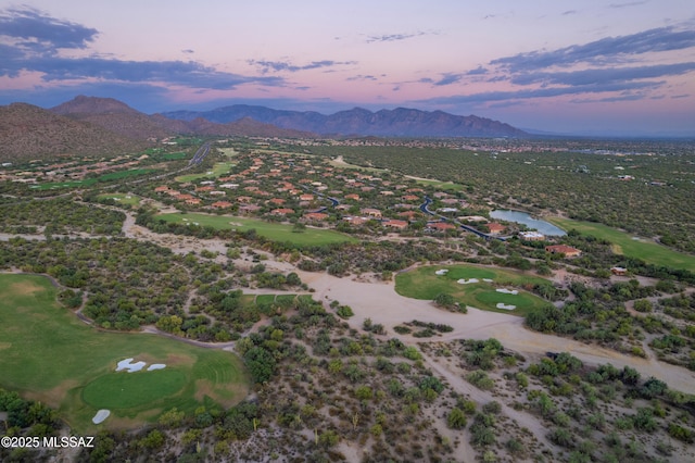 aerial view at dusk featuring golf course view and a water and mountain view