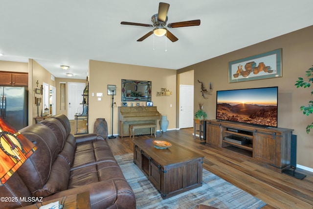 living room featuring wood finished floors, baseboards, and ceiling fan