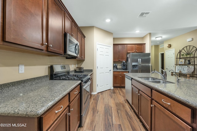 kitchen with visible vents, a sink, appliances with stainless steel finishes, stone countertops, and dark wood-style flooring