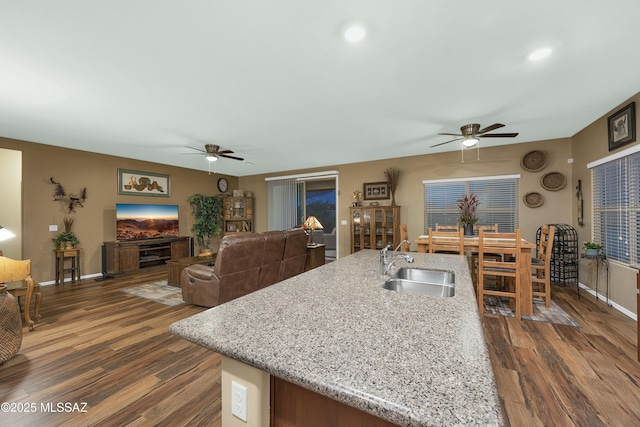 kitchen featuring dark wood finished floors, a ceiling fan, baseboards, and a sink