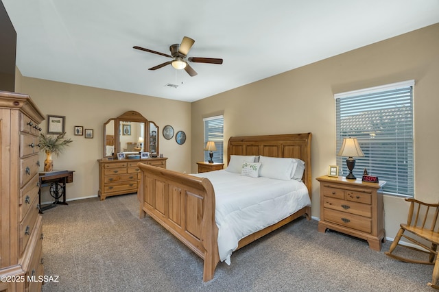 bedroom featuring multiple windows, light carpet, baseboards, and a ceiling fan