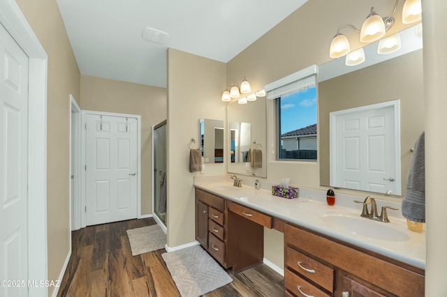 full bathroom with double vanity, a stall shower, wood finished floors, and a sink