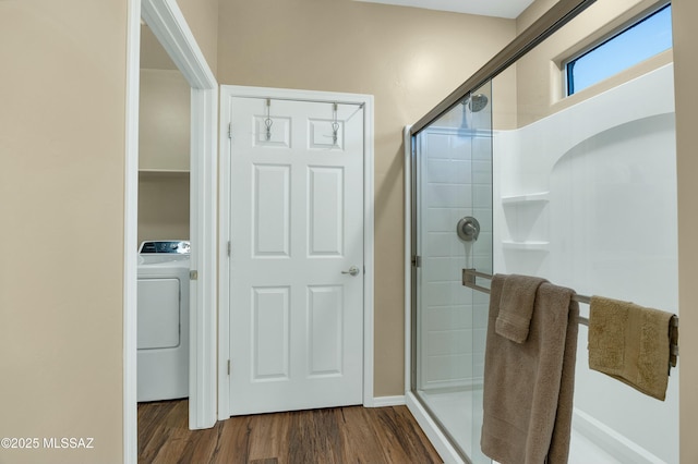 bathroom featuring washer / dryer, wood finished floors, and a shower stall