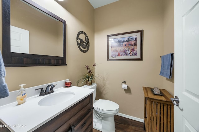 bathroom with baseboards, toilet, wood finished floors, and vanity