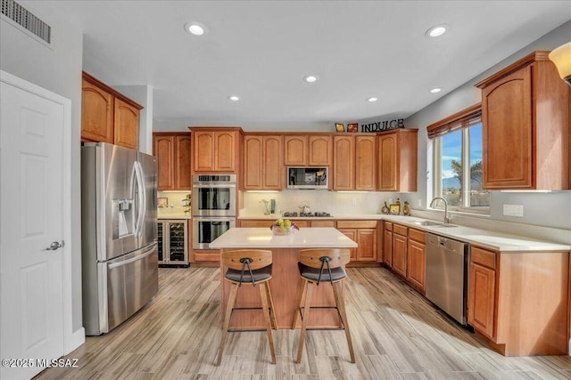 kitchen with visible vents, a breakfast bar, a center island, a sink, and stainless steel appliances
