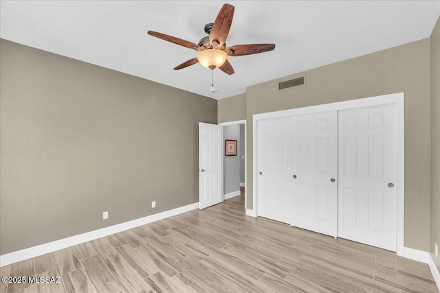 unfurnished bedroom featuring visible vents, baseboards, light wood finished floors, and a closet