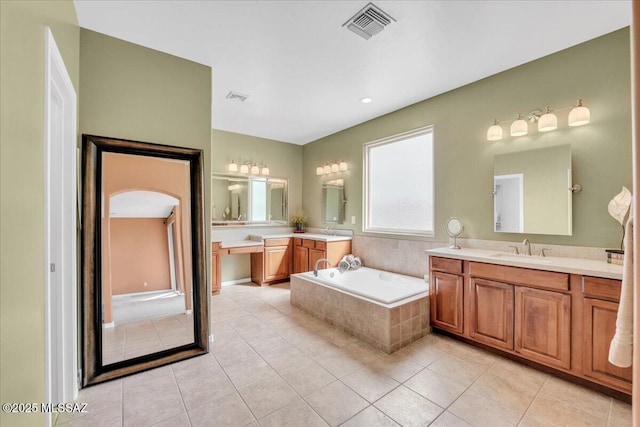 full bathroom with two vanities, tile patterned flooring, a garden tub, visible vents, and a sink