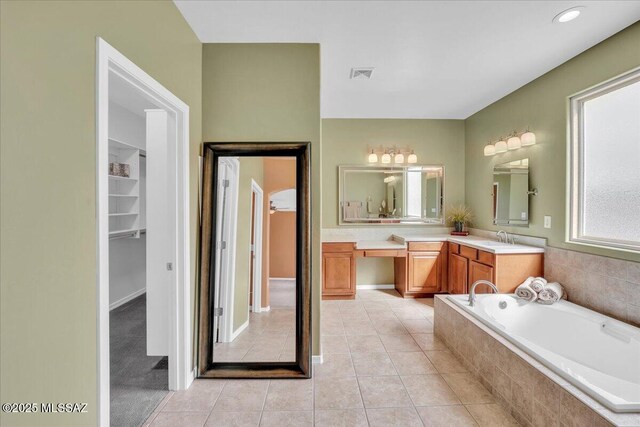 full bathroom featuring vanity, a spacious closet, tile patterned flooring, tiled bath, and visible vents