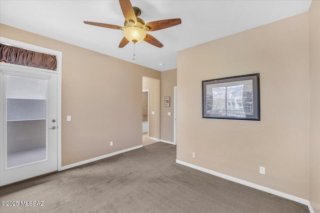 carpeted empty room featuring ceiling fan and baseboards