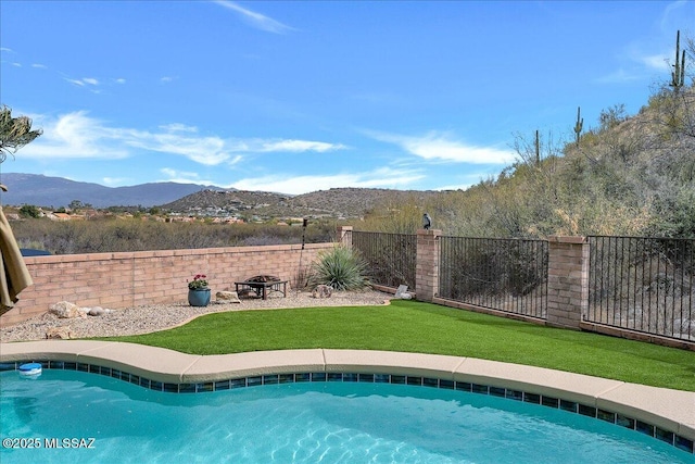 view of swimming pool featuring a yard, a mountain view, and a fenced backyard