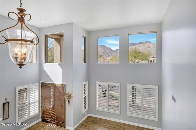 entrance foyer featuring a towering ceiling, a notable chandelier, baseboards, and wood finished floors
