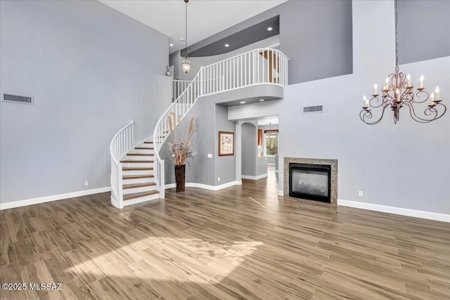 unfurnished living room with visible vents, baseboards, stairway, and a high ceiling