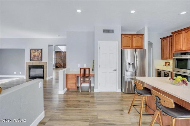 kitchen with baseboards, a fireplace, light countertops, visible vents, and stainless steel appliances