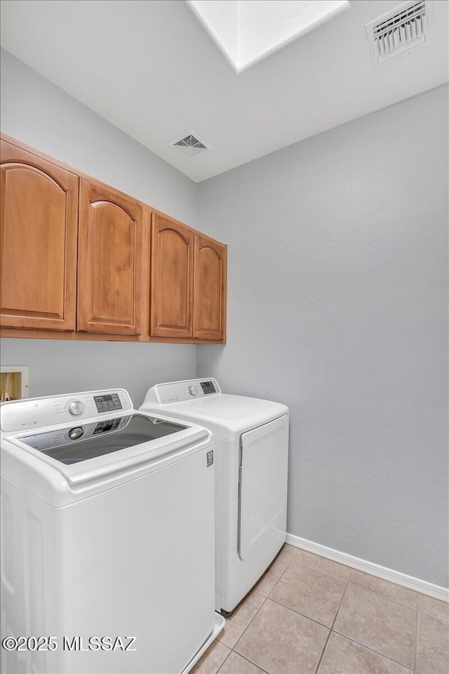 clothes washing area featuring light tile patterned floors, visible vents, washing machine and clothes dryer, baseboards, and cabinet space